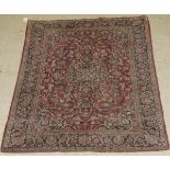 A Kashan rug, the central panel set with a profusely floral decorated medallion on a red ground,