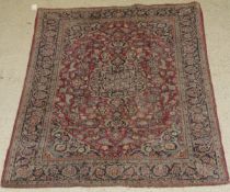 A Kashan rug, the central panel set with a profusely floral decorated medallion on a red ground,