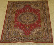 A Persian rug, the central panel set with floral decorated circular medallion on a pink ground,