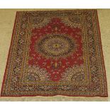 A Persian rug, the central panel set with floral decorated circular medallion on a pink ground,