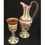 A Victorian Bohemian ruby and enamelled overlaid glass ewer with matching goblet decorated with