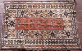 A Turkish rug, the central panel set with geometric designs on a salmon pink and oatmeal ground,