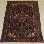 A Caucasian rug, the central panel set with floral decorated medallion on a dark blue ground,