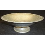 A "Tudric" pewter bowl with scroll decorated rim and hammered body, raised on a foot,