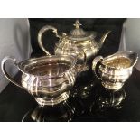 A Victorian/Edwardian silver three piece tea set of oval bellied form with embossed decoration