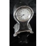A George V silver cased mantle clock of small proportions with ribbon, reeded and cross decoration,