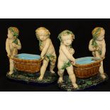 A pair of 19th Century Minton majolica table pieces as putti carrying coopered wine coolers raised