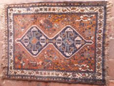 A Shiraz rug, the central panel set with two joined lozenge shaped medallions on a brown ground,