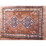 A Shiraz rug, the central panel set with two joined lozenge shaped medallions on a brown ground,