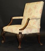 A George II walnut library chair, the upholstered back and open arms with swept and carved supports,