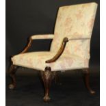 A George II walnut library chair, the upholstered back and open arms with swept and carved supports,