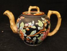 A 19th Century pottery teapot of bullet form decorated with blossoming branches on a black ground,
