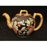 A 19th Century pottery teapot of bullet form decorated with blossoming branches on a black ground,