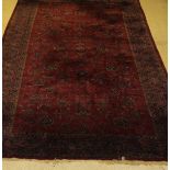 A Persian rug, the central panel with repeating floral sprays on a puce ground,