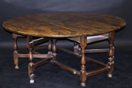 An 18th Century elm plank topped oval gate-leg dining table,
