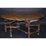 An 18th Century elm plank topped oval gate-leg dining table,