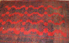 A Donegal carpet, the central panel set with repeating designs in blue and green, on a red ground,