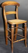A 19th Century stained beech child's deportment chair with bar back, caned seat,
