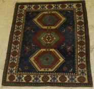A Caucasian rug, the central panel set with three lozenge shaped medallions within a blue ground,