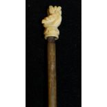 A 19th Century rhino horn pointer of tapering form, the handle as carved ivory hand clasping leaf,