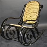An ebonised framed bentwood rocking chair with cane seat and back by Thonet,
