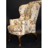 An early 18th Century upholstered wing back scroll arm chair,