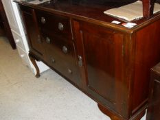 A 1920's mahogany sideboard with three drawers flanked by two cupboard doors on cabriole front legs
