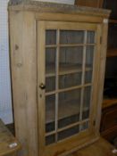 A pine hanging corner cabinet with glazed and barred door