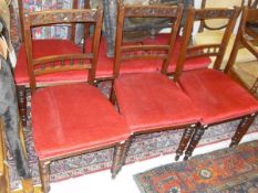 A set of six Edwardian walnut framed dining chairs with carved top rail above red upholstered seats