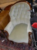 A Victorian walnut framed button backed salon chair with carved decoration raised on scroll front