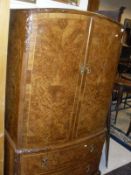 A 1930's burr walnut and cross banded and herringbone strung bow fronted linen press with acanthus