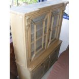 A pine kitchen cabinet with two glazed doors over two drawers and two cupboard doors