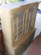 A pine kitchen cabinet with two glazed doors over two drawers and two cupboard doors