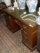 A Victorian mahogany desk the tooled and gilded leather insert writing surface over a central
