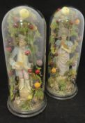 Two Continental figures housed set in a naturalistic setting of fruit on branches housed in a glass