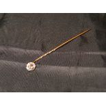 A yellow metal mounted stick pin with single diamond in a claw setting approx .0.