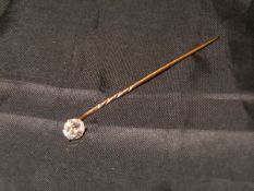 A yellow metal mounted stick pin with single diamond in a claw setting approx .0.