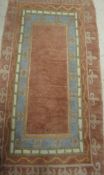 A Tibetan rug, the central panel of plain pink ground within a stepped pink, blue,