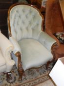 A Victorian walnut framed button backed salon chair with carved decoration raised on scroll front