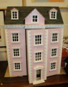 A painted pink dolls town house with varrious furniture etc.