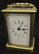 A brass and glass cased carriage clock with Roman numerals to the enamelled dial