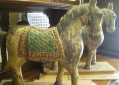 A pair of Eastern carved wood horses with painted saddles and bodies,
