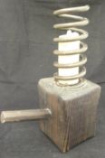 A candlestick in the form of a coil on a pine block with a pine handle,