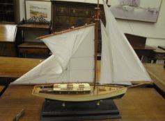 A model of a tall-masted sailing boat, painted in cream and black,