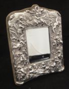 A sterling silver and embossed framed mirror decorated with putti and Venus cavorting amongst