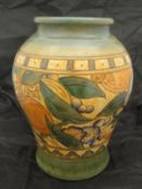 A Charlotte Rhead Bursley Ware vase decorated with band of fruit and flowers on a terracotta ground