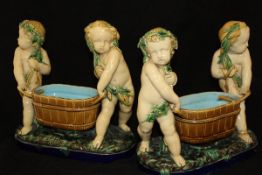 A pair of 19th Century Minton majolica table pieces as putti carrying coopered wine coolers raised