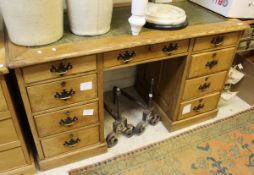 A pine pedestal desk with green leather tooled inset top and nine assorted drawers to whole on