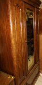 A Victorian mahogany single mirrored door wardrobe above a single drawer