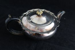 A George V silver teapot of squat form with pie crust rim and ivory finial and ebonised handle (by